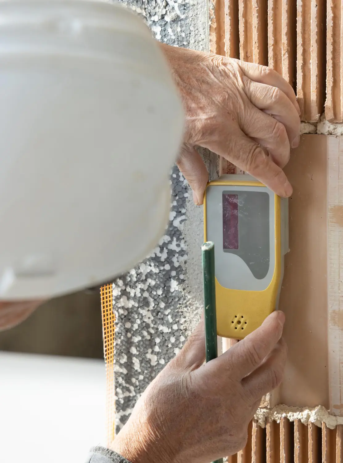 Herrn Lippertz prüft an einer Wand die Feuchtigkeit und ein Gutachten zu erstellen
